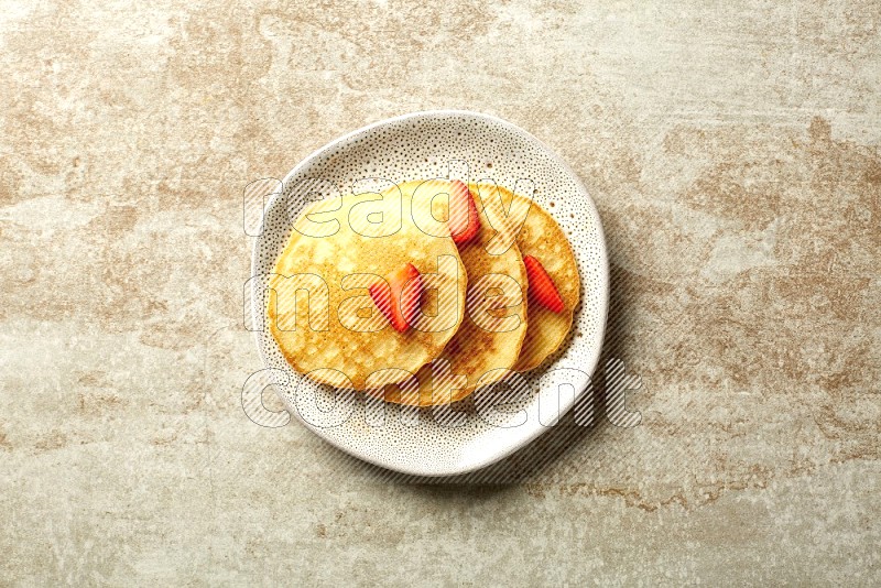 Three stacked strawberry pancakes in an irregular plate on beige background