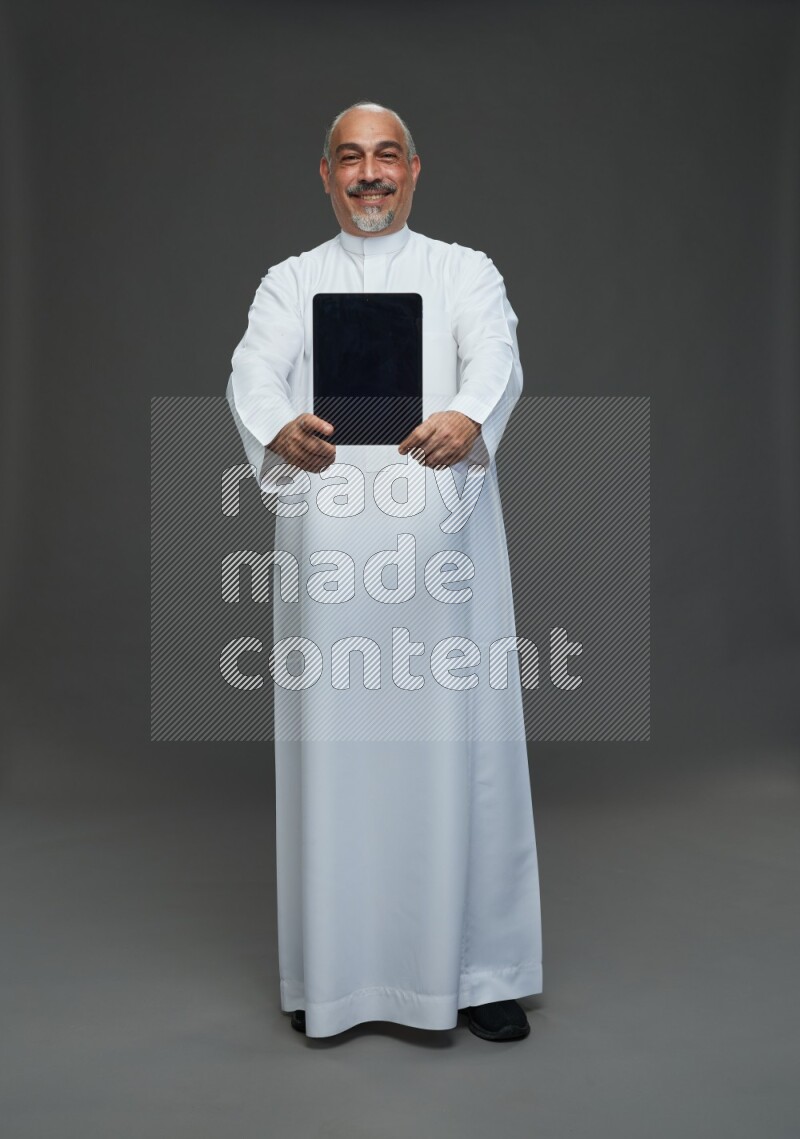 Saudi man without shomag Standing working on tablet on gray background