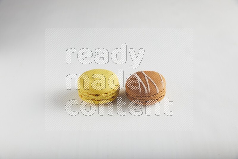 45º Shot of of two assorted Brown Irish Cream, and Yellow Lemon macarons on white background