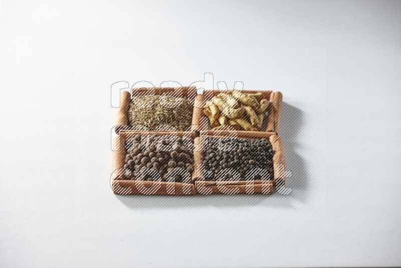 4 مربعات من أعواد القرفة ممتلئة بالكمون وأصابع الكركم وبهار الفلفل الحلو وحبوب الفلفل الأسود على أرضية بيضاء