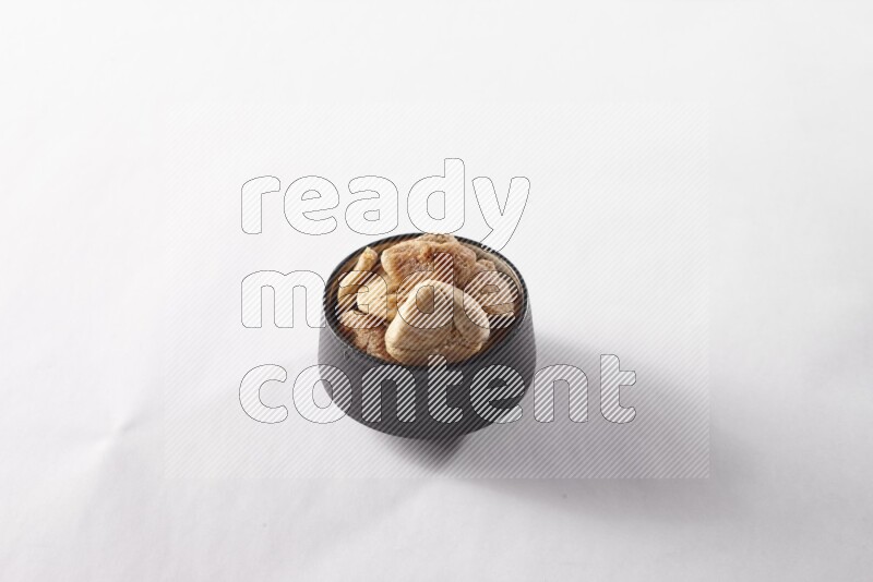 Dried figs in a black pottery bowl on white background