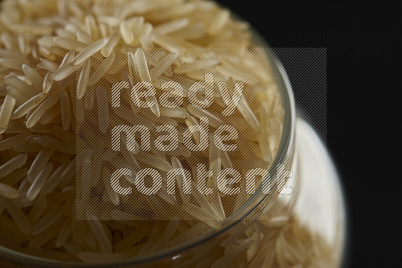 Basmati golden rice in a glass jar on black background