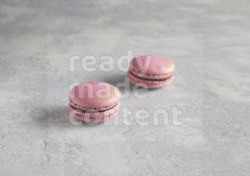 45º Shot of two Purple Strawberry macarons on white  marble background