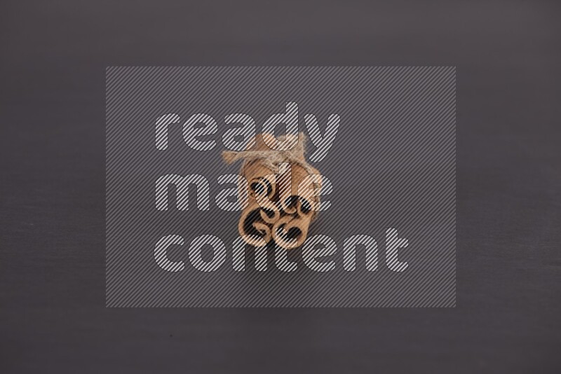 4 أعواد من القرفة مربوطة علي خلفية سوداء