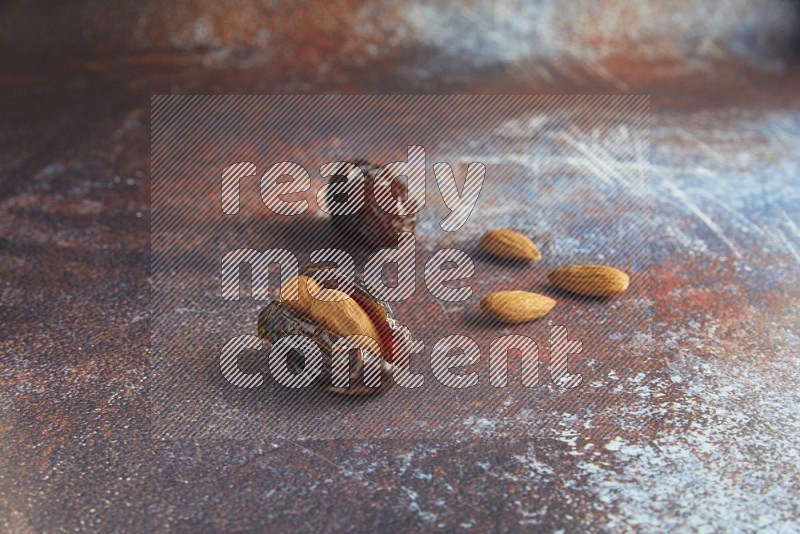 two almond stuffed madjoul dates on a rustic reddish background