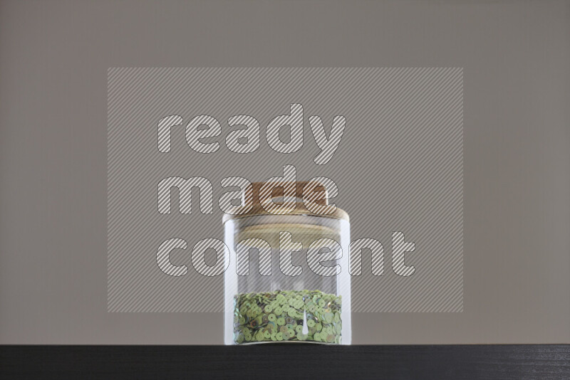 Sequins in a glass jar on black background