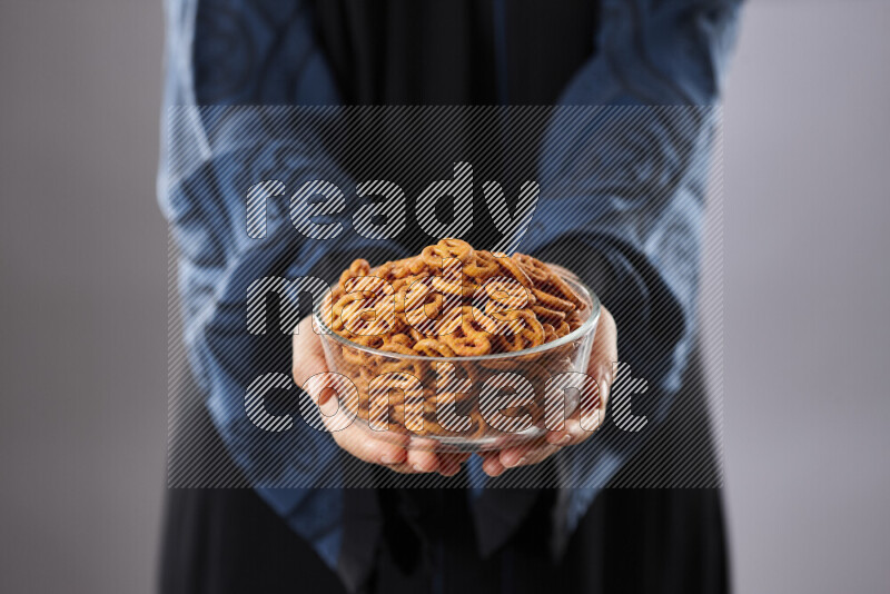 Woman in abaya holding different kinds of snacks in different positions