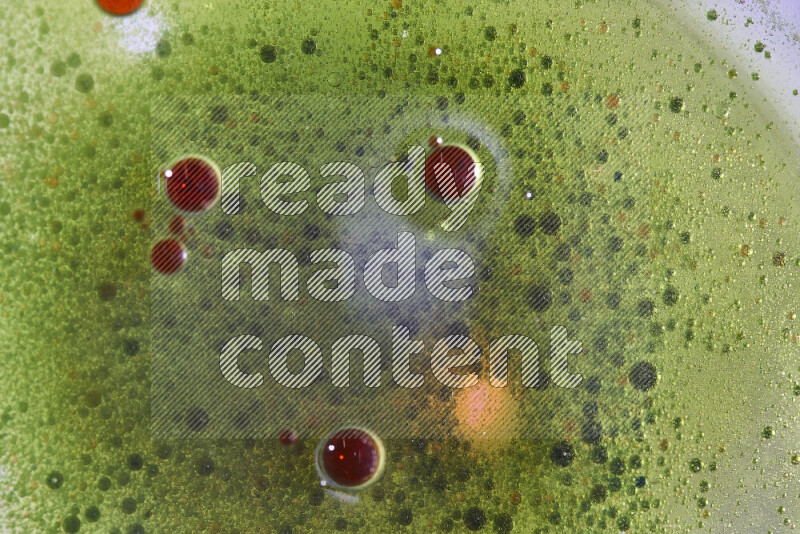 Close-ups of abstract red and green watercolor drops on oil Surface on green background