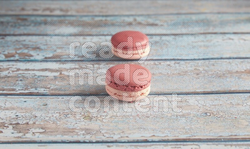 45º Shot of two Pink Litchi Raspberry macarons on light blue wooden background