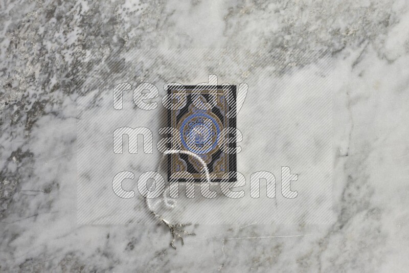 Quran with a prayer beads on grey marble background