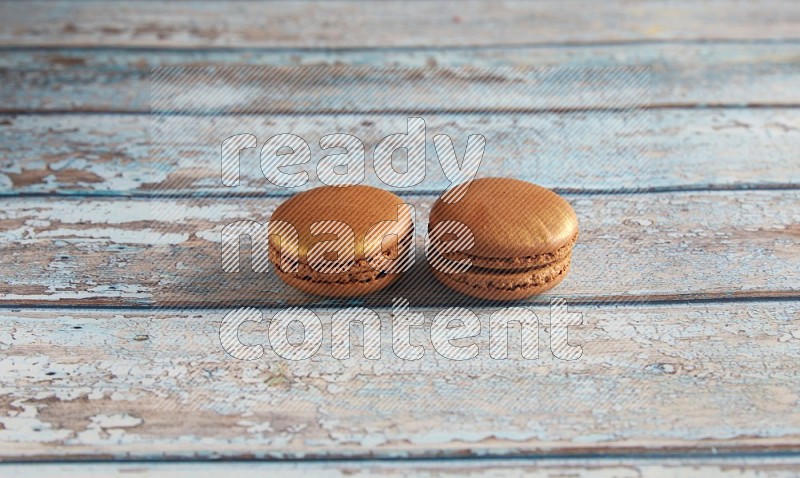 45º Shot of two Brown Coffee macarons on light blue wooden background