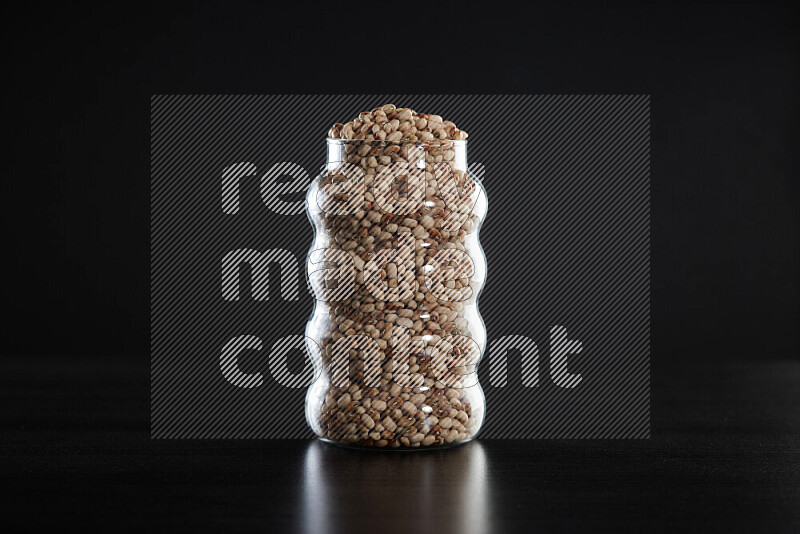 Black-eyed peas in a glass jar on black background