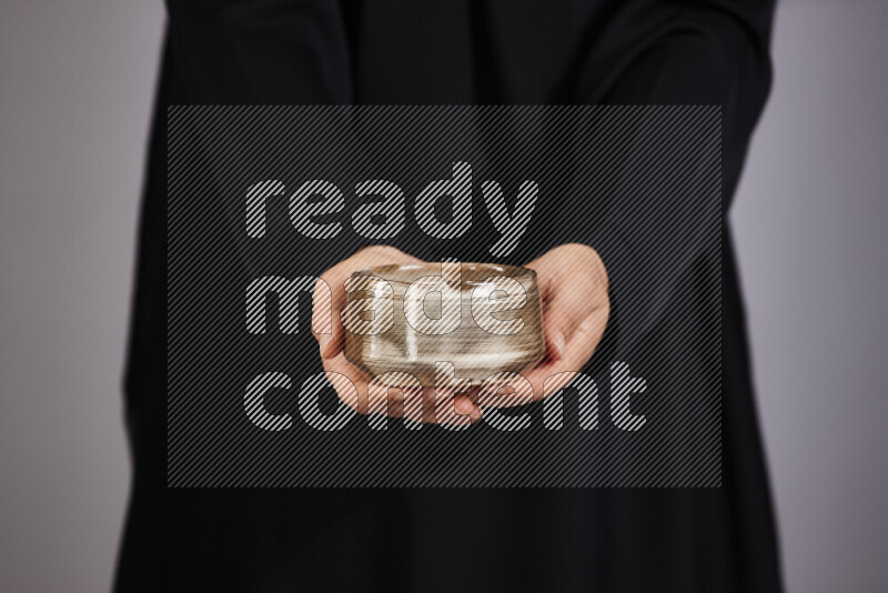 A woman in black abaya holding different pottery essentials in different positions