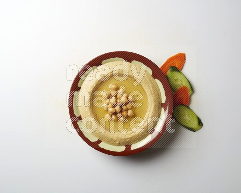 Hummus in a traditional plate garnished with roasted chickpeas  on a white background