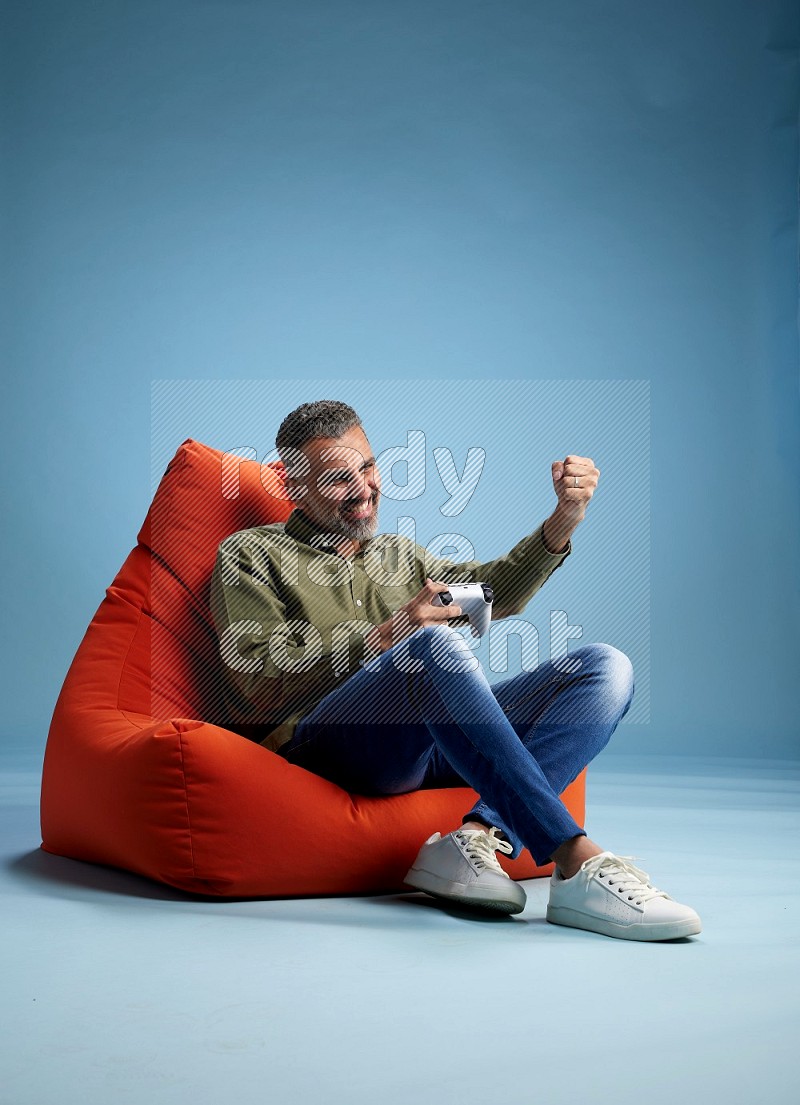 A man sitting on an orange beanbag and gaming with joystick