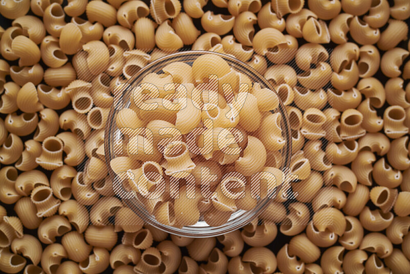 Pipe pasta in a glass bowl on black background