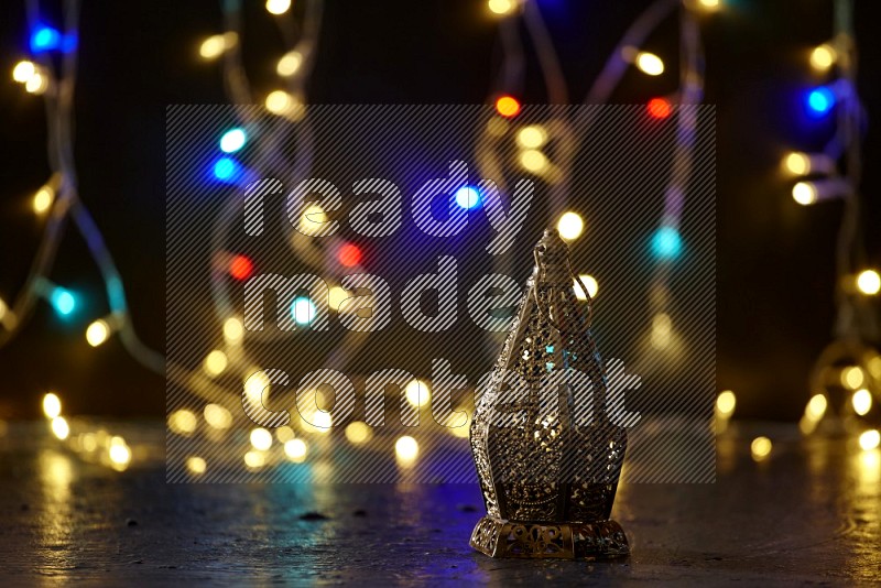 A traditional ramadan lantern surrounded by glowing fairy lights in a dark setup