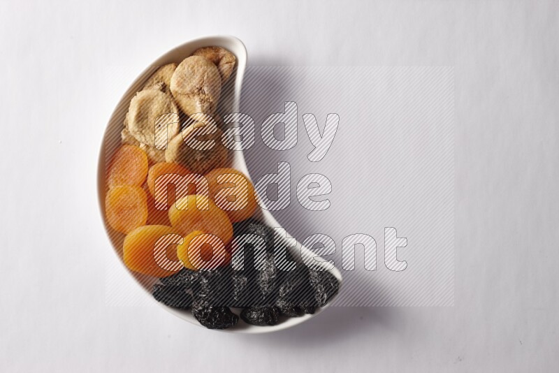 Mixed Dried fruits in a crescent pottery plate on white background