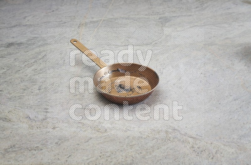 A Small Copper Pan On Grey Marble Flooring