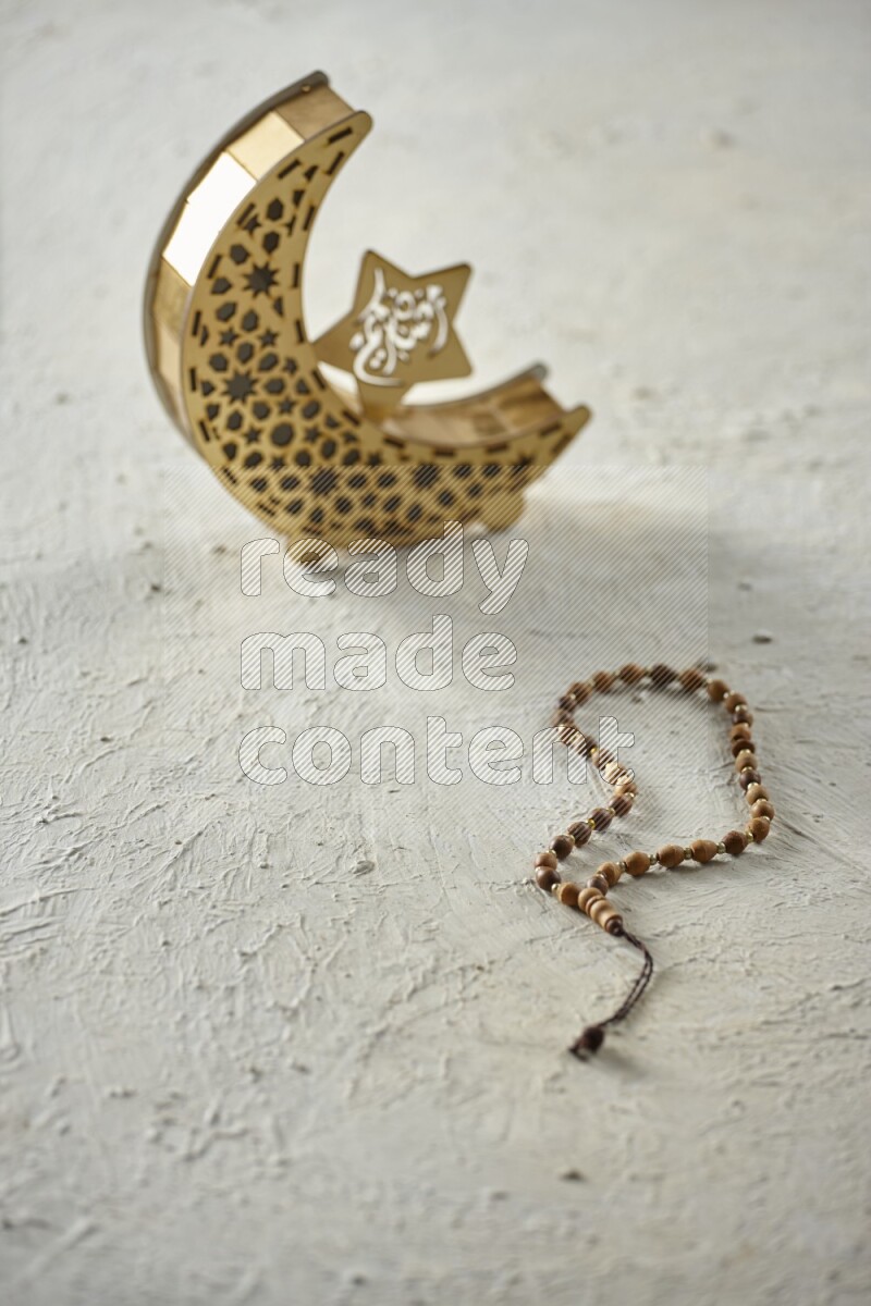 A wooden golden crescent lantern with different drinks, dates, nuts, prayer beads and quran on white background