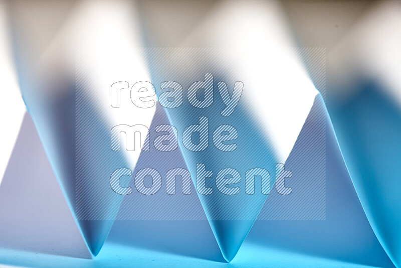 A close-up abstract image showing sharp geometric paper folds in white and blue gradients