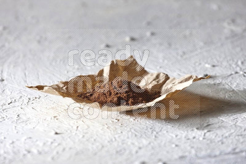 Cloves powder on crumpled piece of paper on a textured white flooring