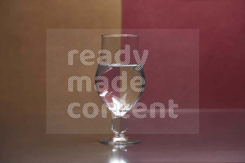 The image features a clear glassware filled with water, set against brown and dark red background