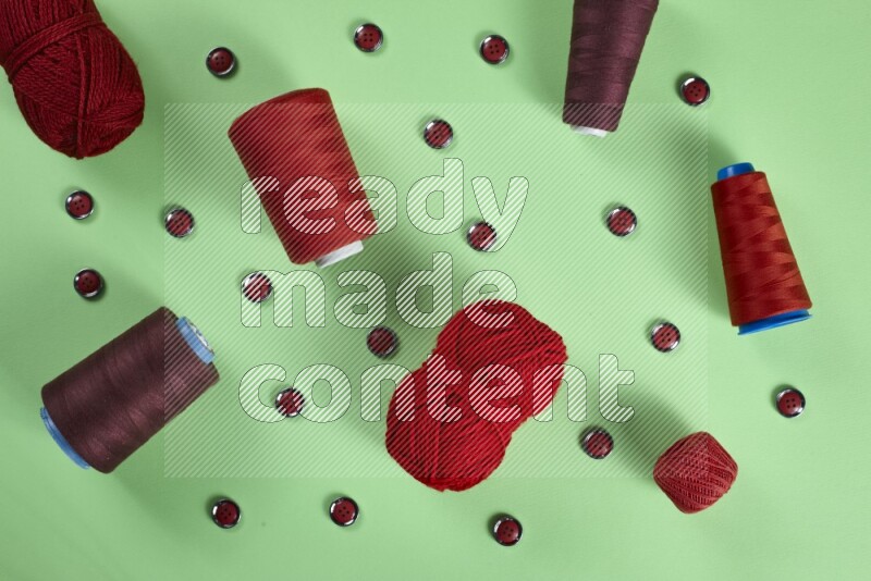 مجموعة من أدوات الخياطة والتفصيل حمراء اللون على خلفية خضراء