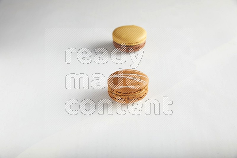 45º Shot of of two assorted Brown Irish Cream, and Yellow, and Brown Chai Latte macarons on white background