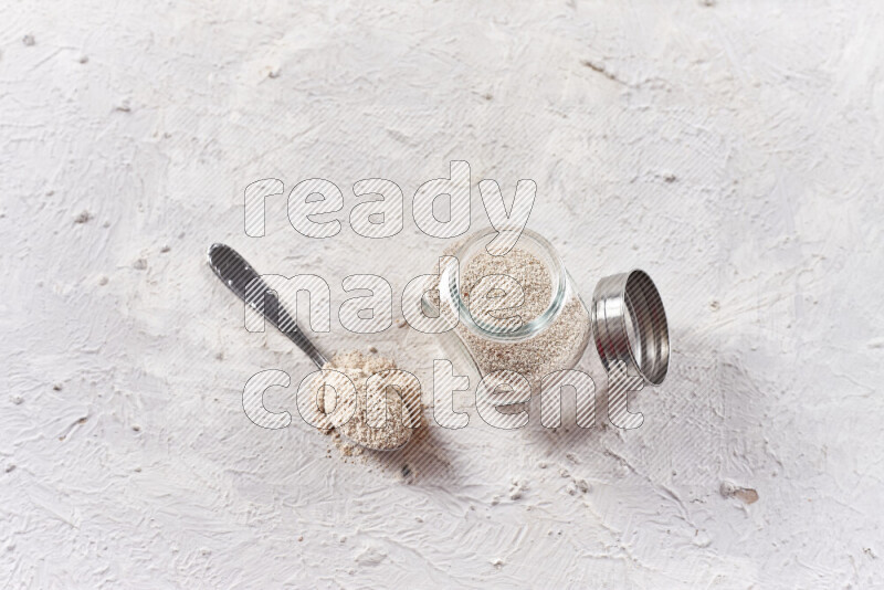 A glass jar full of onion powder on white background