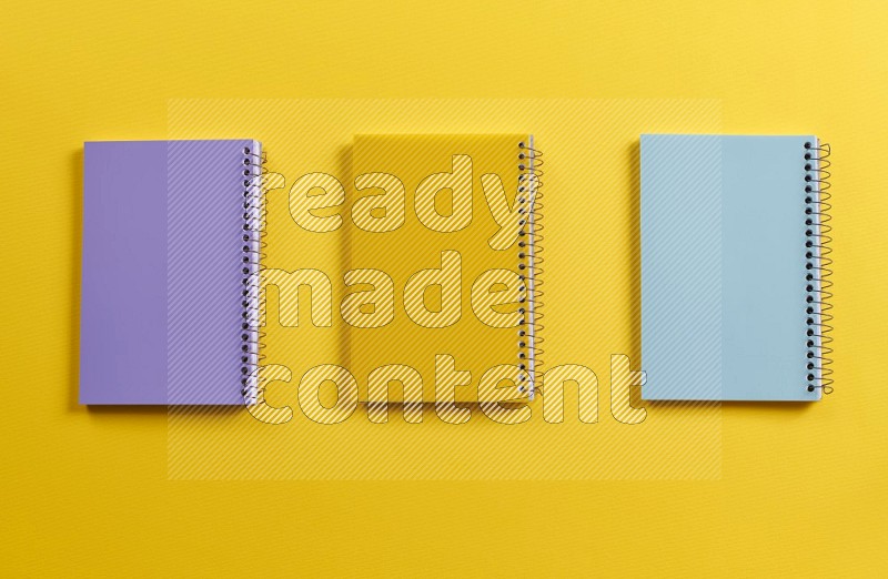 Multicolored notebooks on yellow background (Back to school)