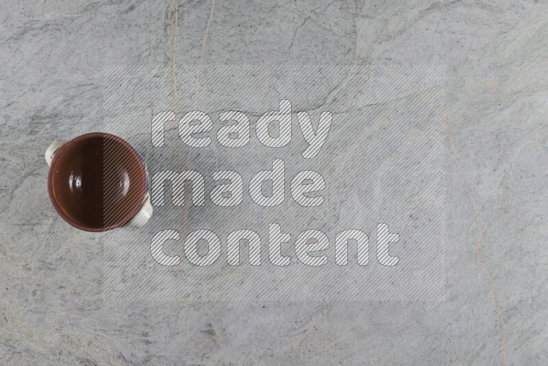 إناء فخاري متعدد الألوان مع غطائه على خلفية من الرخام الرمادي