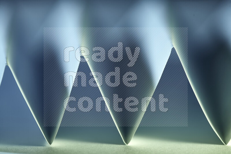 A close-up abstract image showing sharp geometric paper folds in green and blue gradients