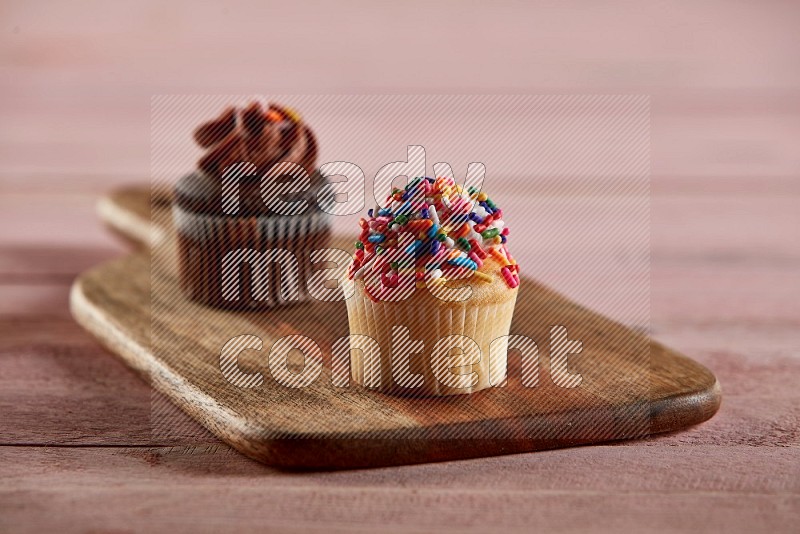 Vanilla mini cupcake topped with sprinkles on a wooden board