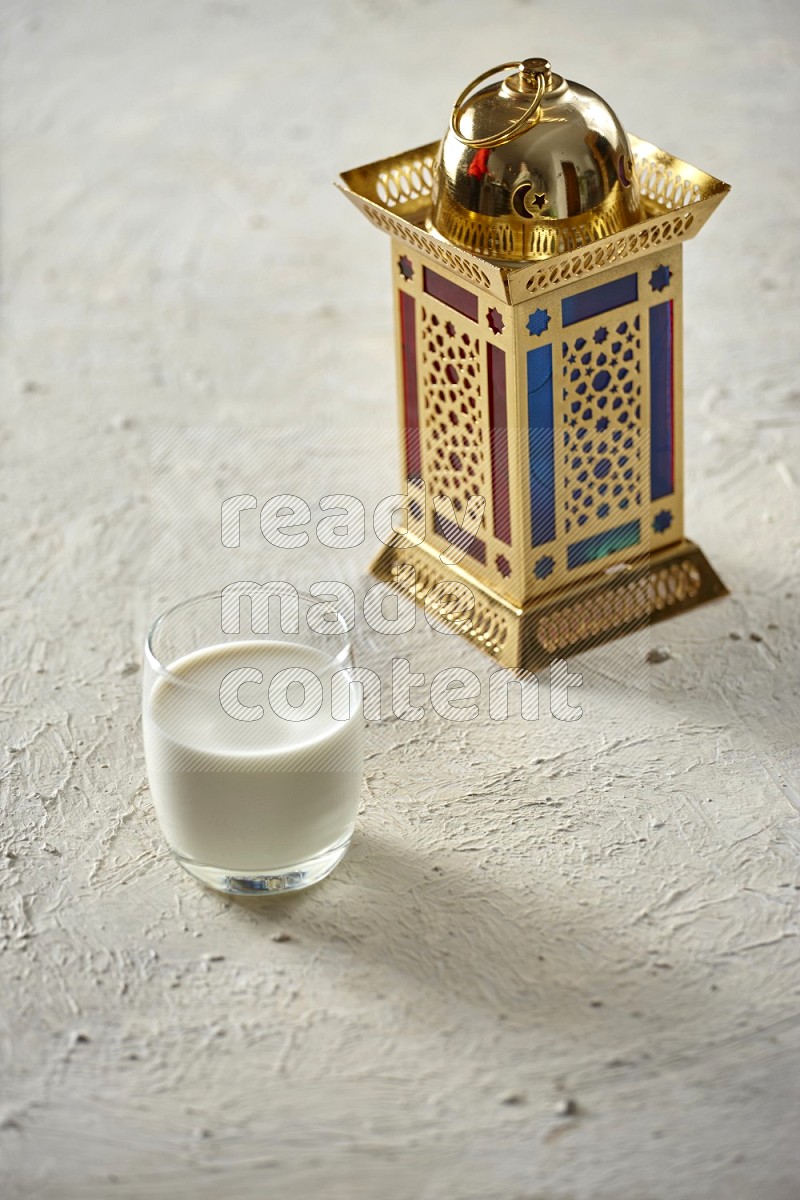 A golden lantern with drinks, dates, nuts, prayer beads and quran on textured white background