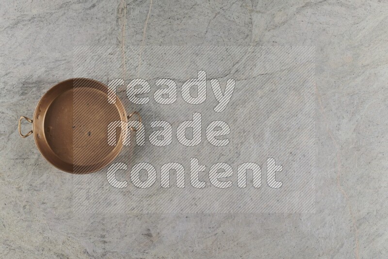 A small copper pan on grey marble background