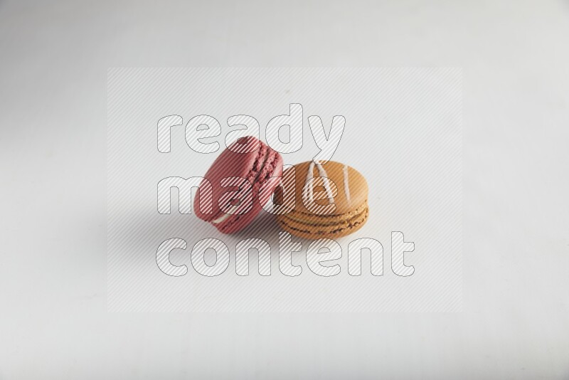45º Shot of of two assorted Brown Irish Cream, and Red Velvet macarons on white background