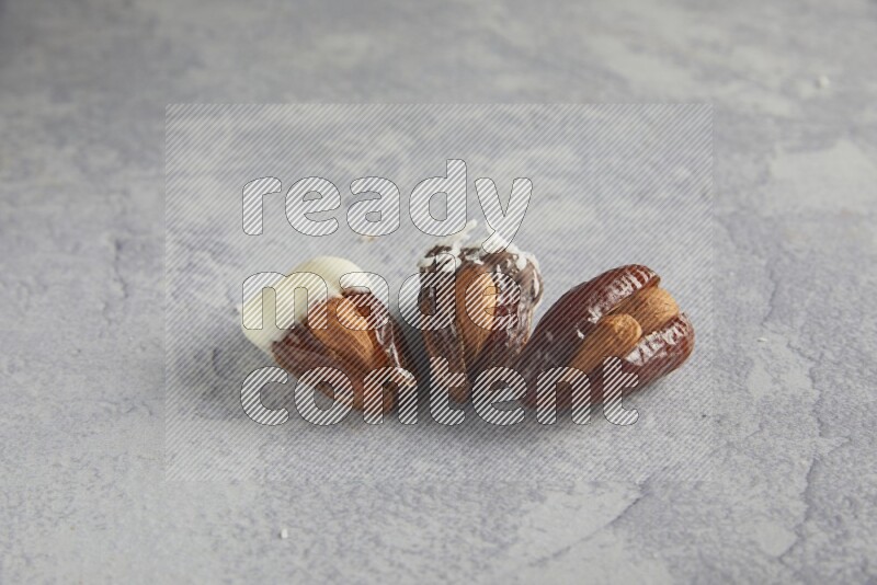 Three Almond stuffed dates plain and covered with chocolate on a light grey background