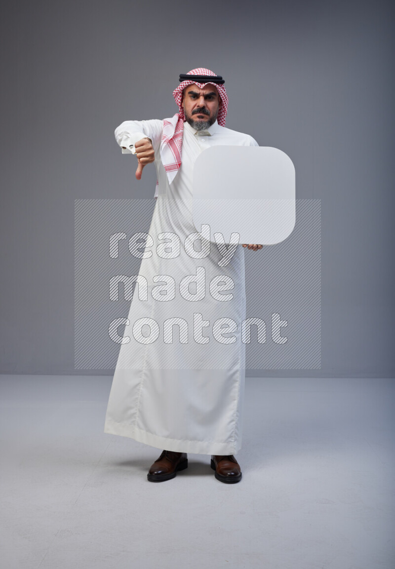 Saudi man Wearing Thob and red Shomag standing holding social media sign on Gray background