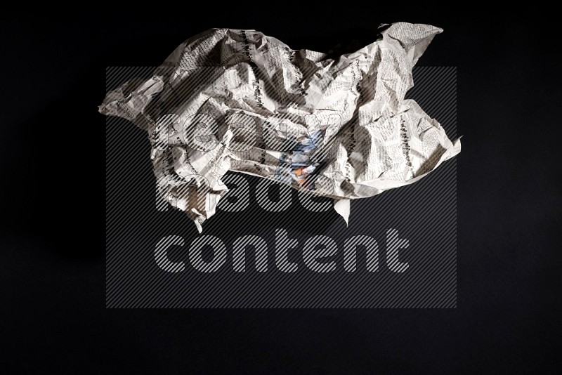 Crumpled newspaper sheet on black background