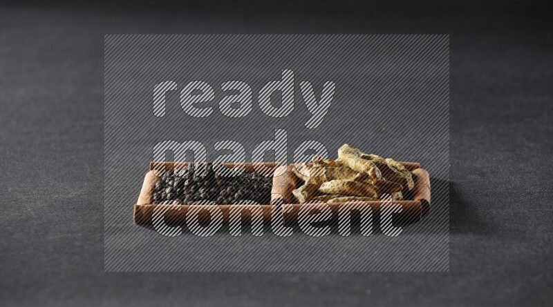 2 squares of cinnamon sticks full of black peppers and turmeric fingers on black flooring