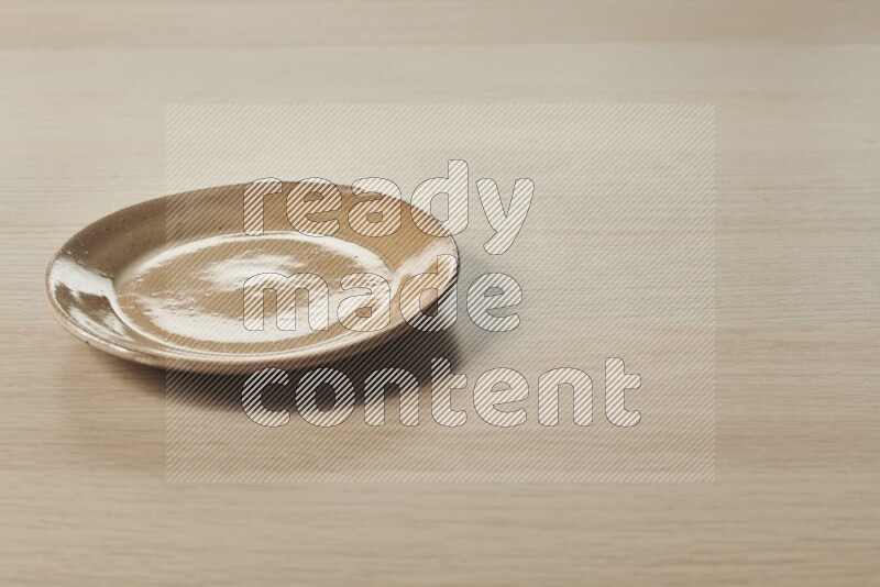 A beige pottery plate on light wooden background