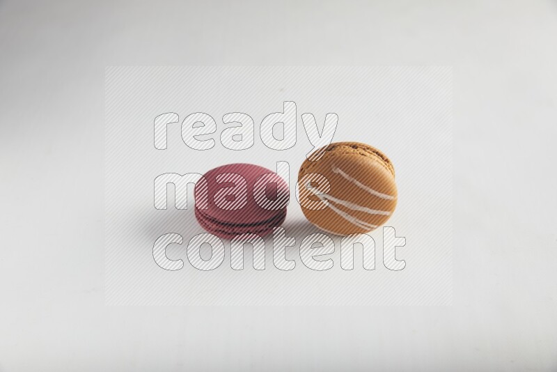 45º Shot of of two assorted Brown Irish Cream, and Red Cherry macarons on white background
