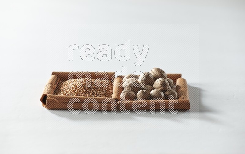 2 squares of cinnamon sticks full of mustard seeds and nutmegs on white flooring