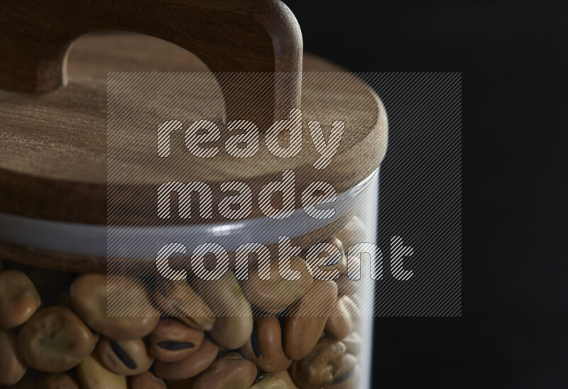 Fava beans in a glass jar on black background
