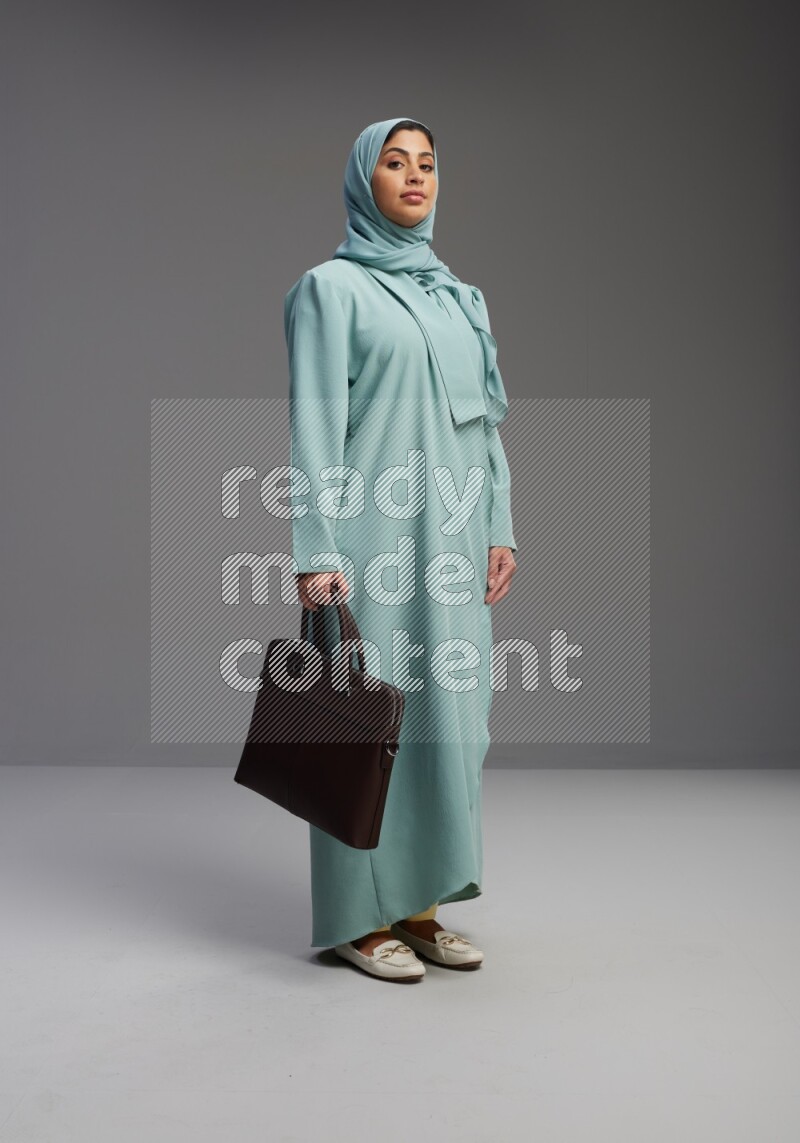 Saudi Woman wearing Abaya standing holding bag on Gray background