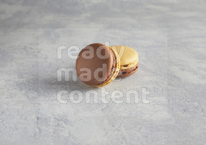 45º Shot of two Yellow and Brown Chai Latte macarons r on white  marble background