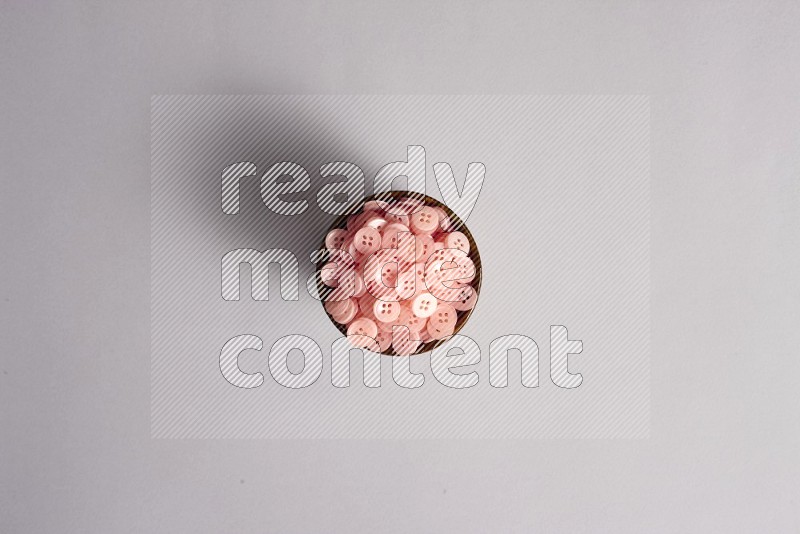 A multicolored pottery bowl full colored buttons on grey background