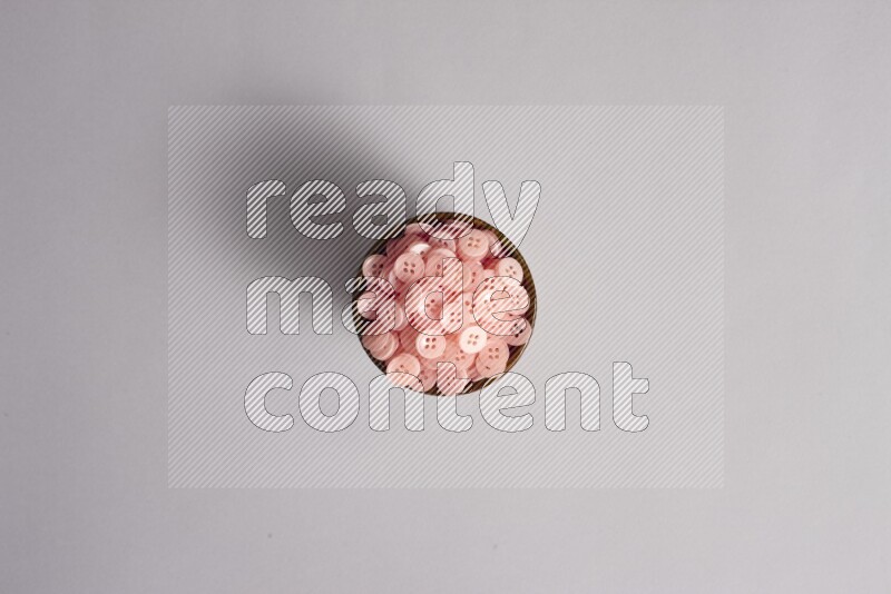 A multicolored pottery bowl full colored buttons on grey background