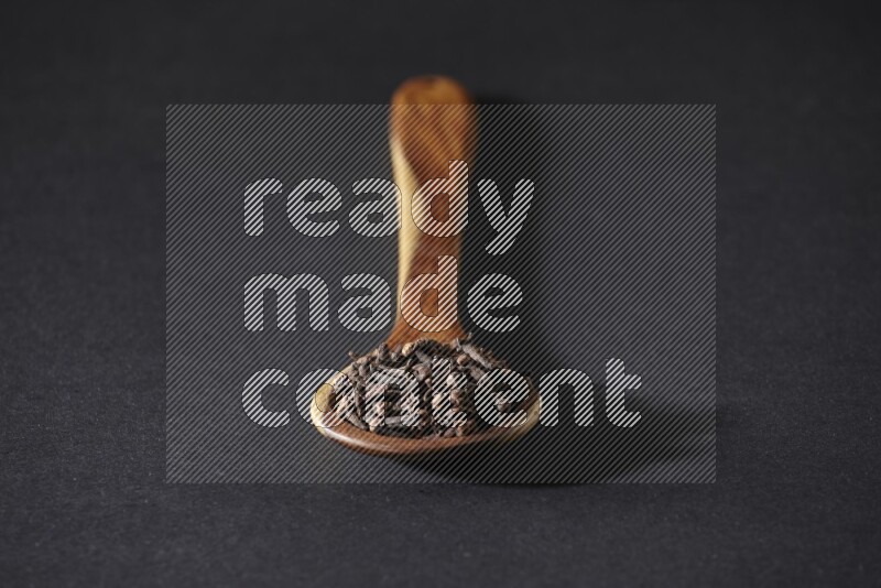 حبوب القرنفل في ملعقة خشبية علي خلفية سوداء